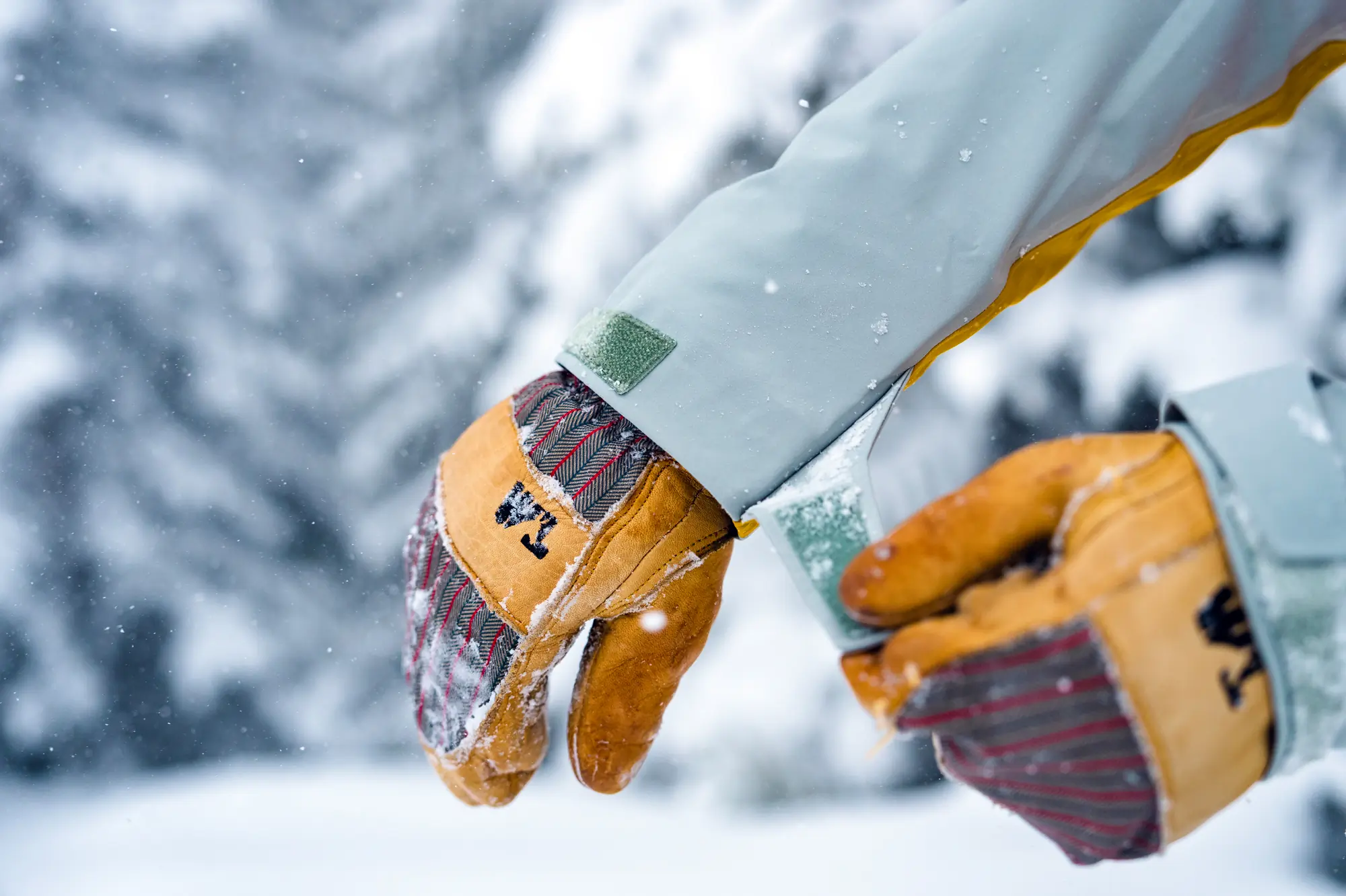 A close-up of a hand tightening the velcro cuff strap on a winter glove.