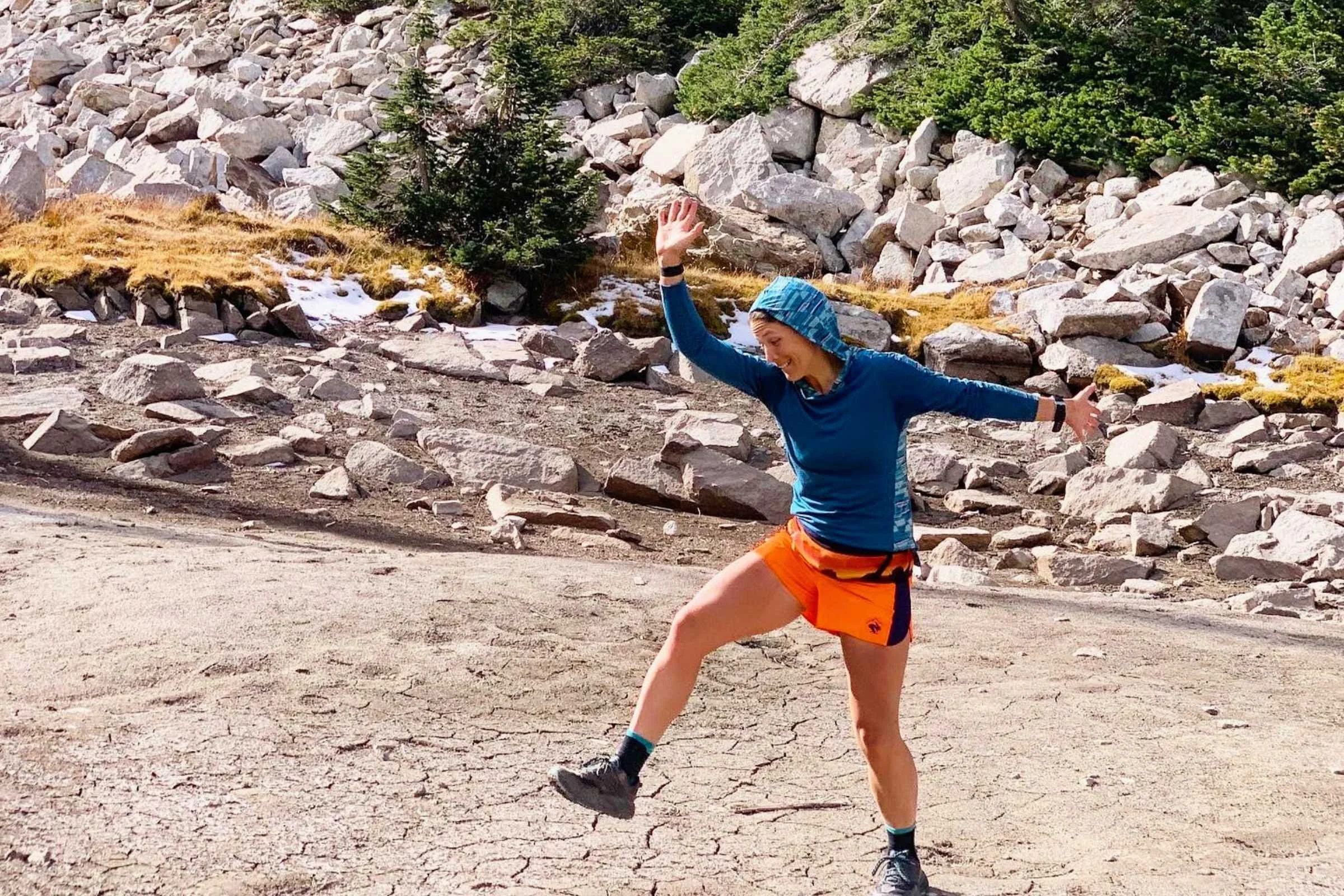 A woman trail running in a winter environment wearing a form-fitting charcoal base layer.