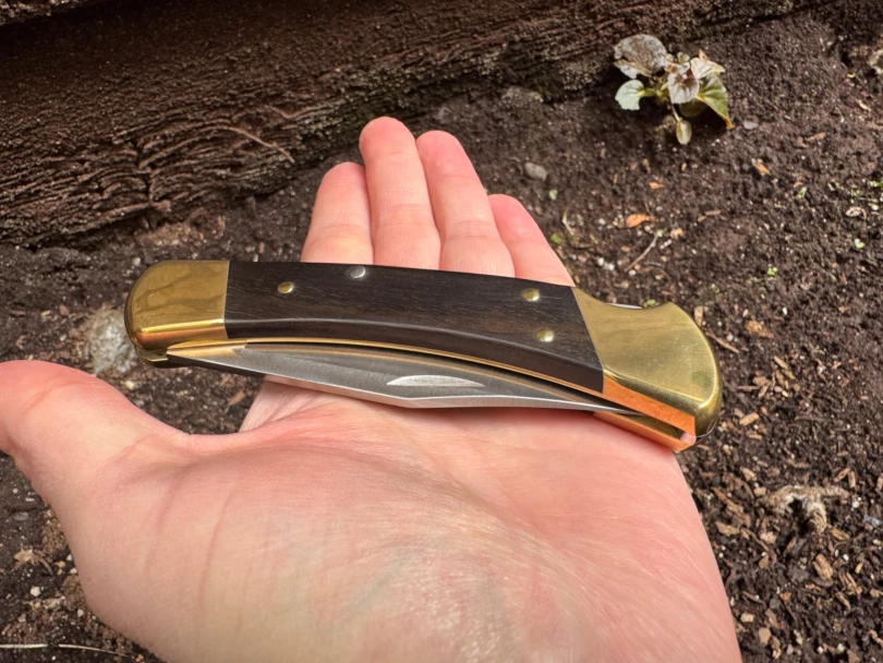 A person holding an open Buck 110 knife to show its size relative to the hand.