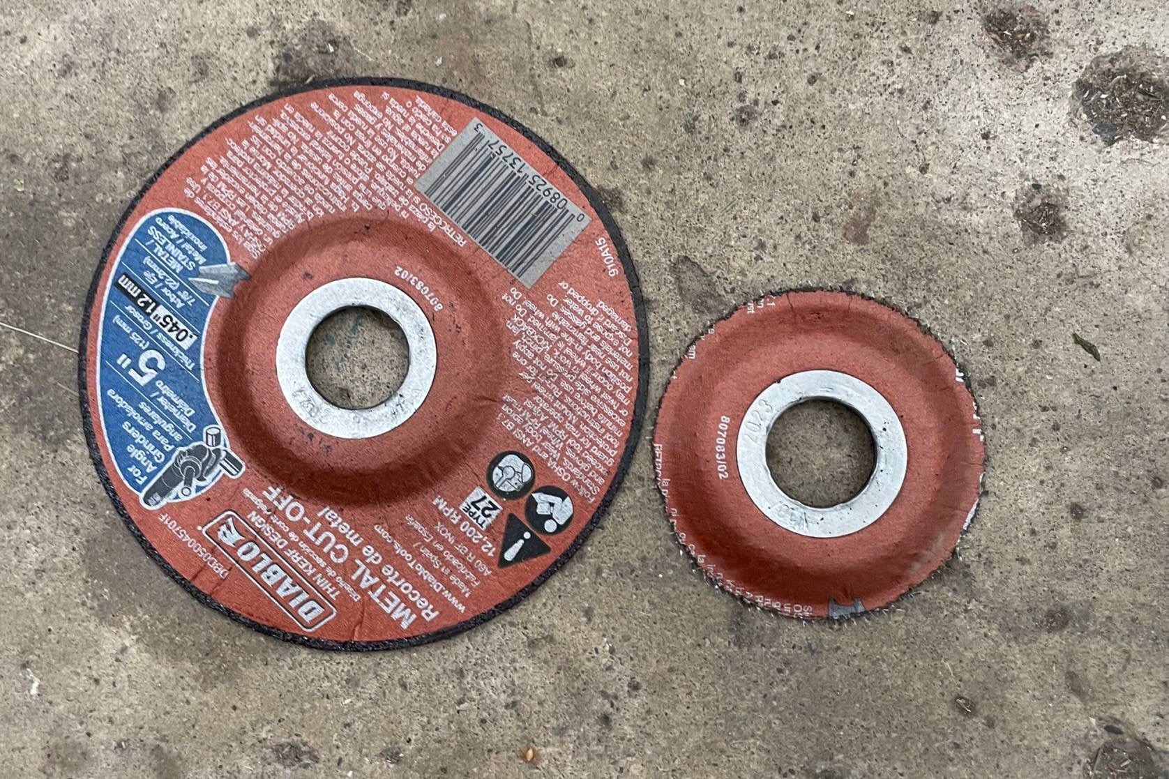 Two angle grinder wheels, one brand new and one completely worn down after trying to cut a Hiplok D1000.