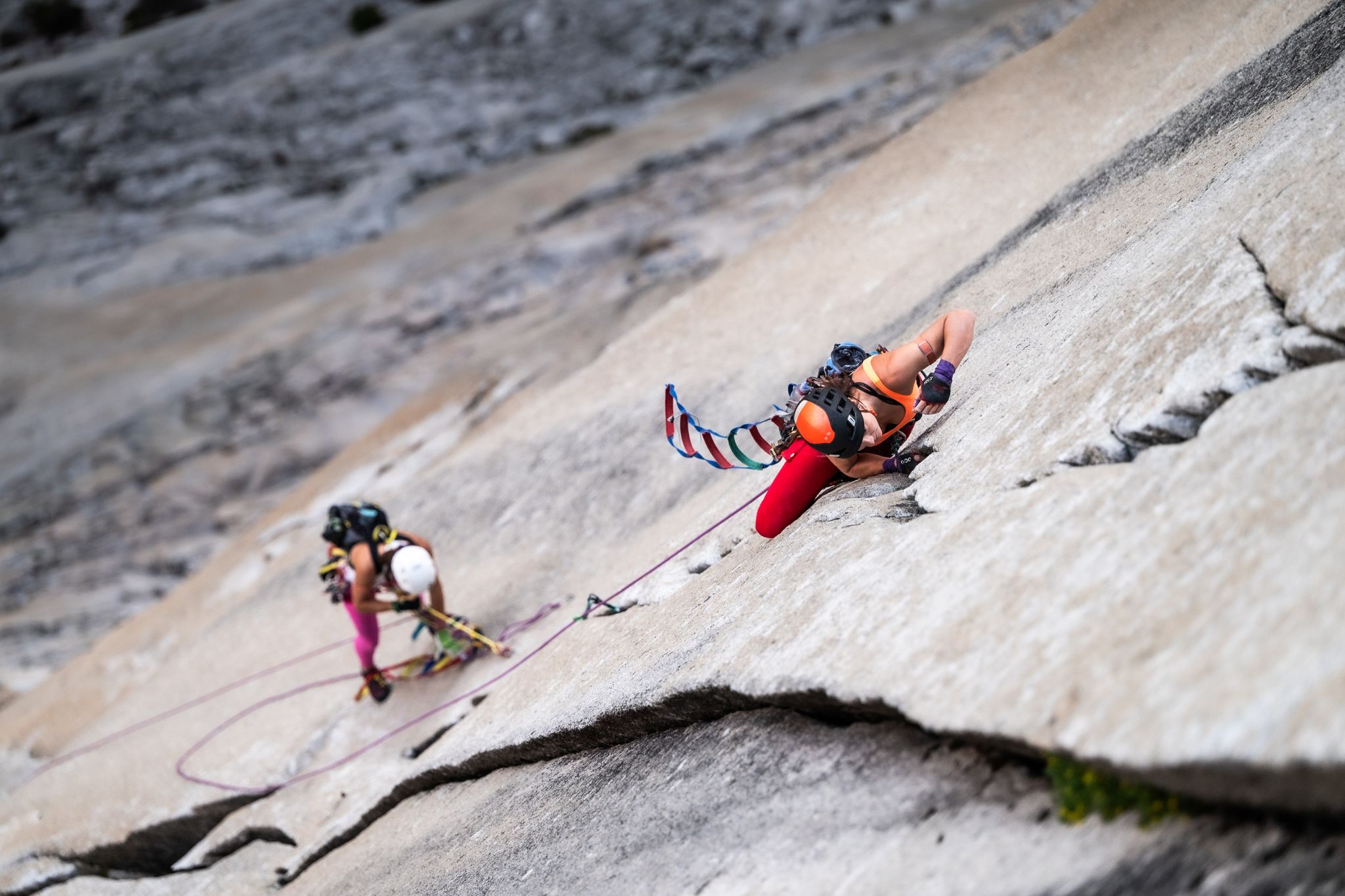 Two women climbing a multi-pitch vertical wall in Yosemite National Park.