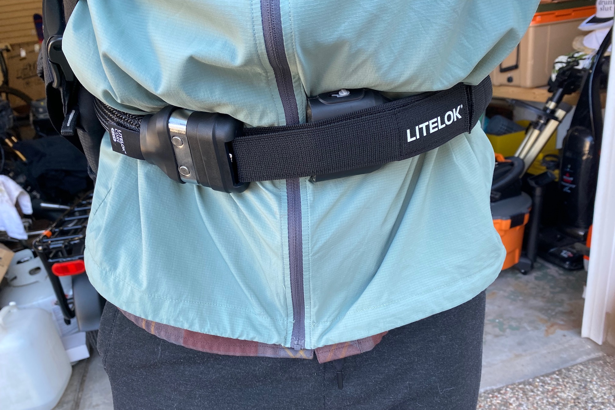 A cyclist wearing a Litelok Core Plus lock around their waist while riding a bike.