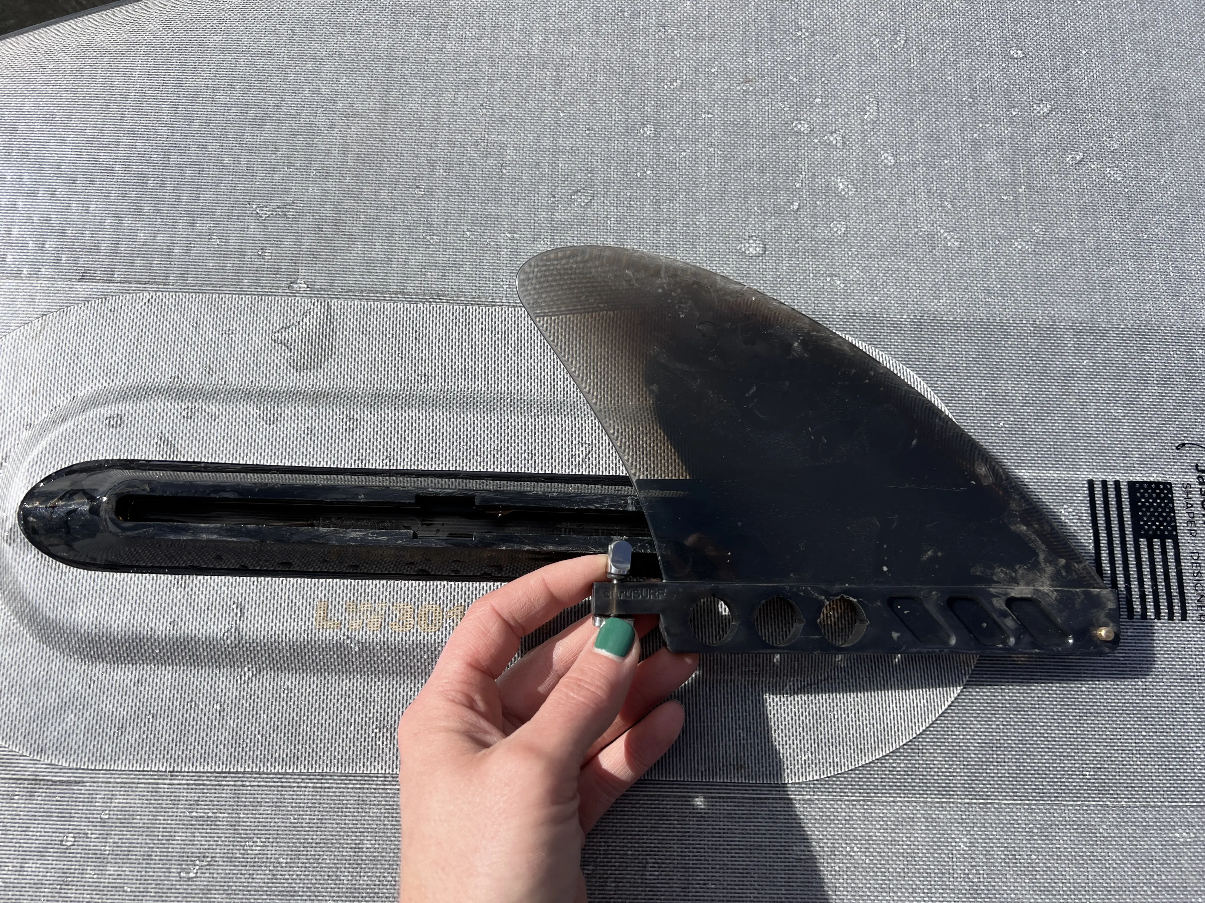 Close-up view of a single tracking fin on the tail of a hard standup paddleboard.