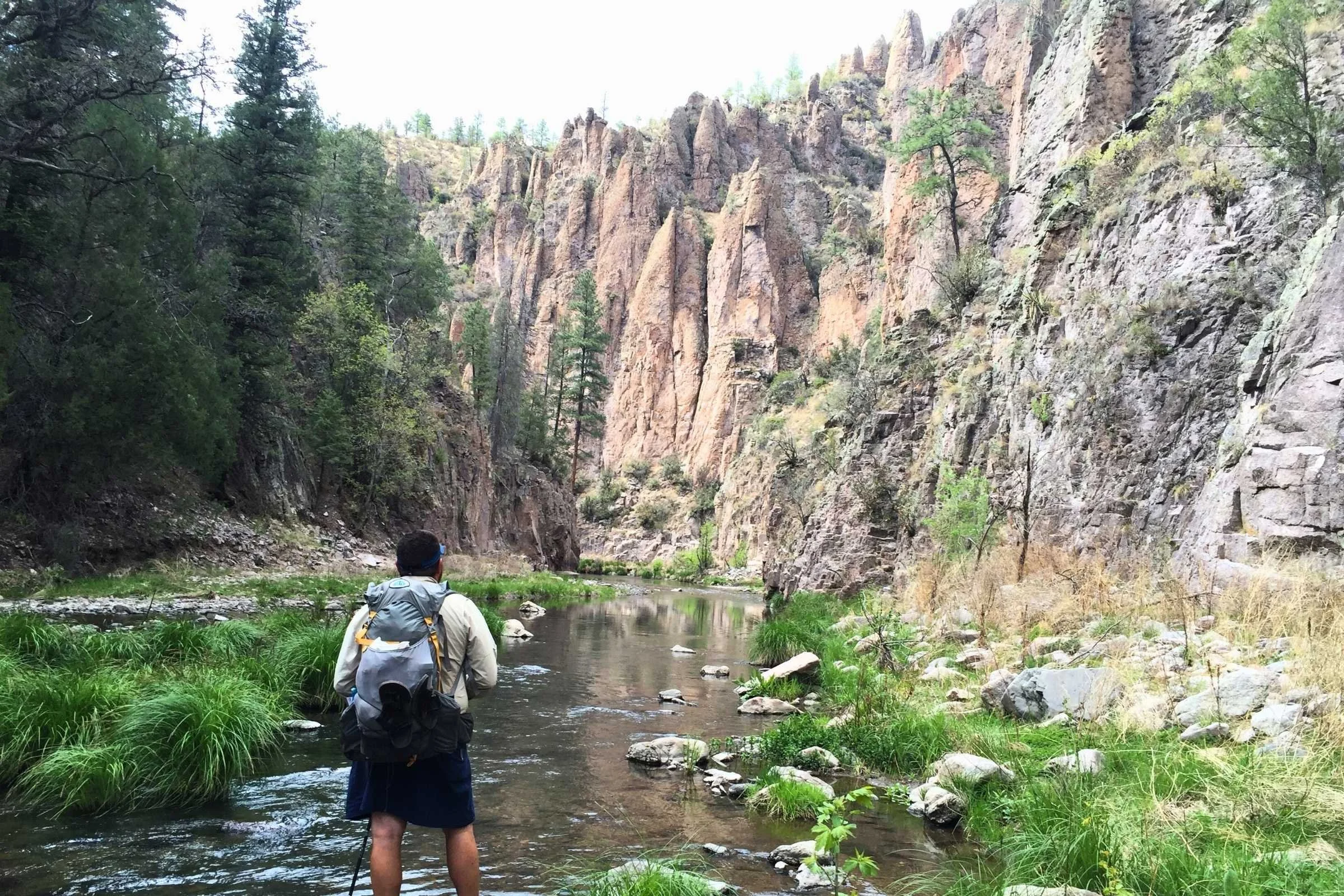 A Panasonic Lumix rugged camera partially buried in thick river mud and water.