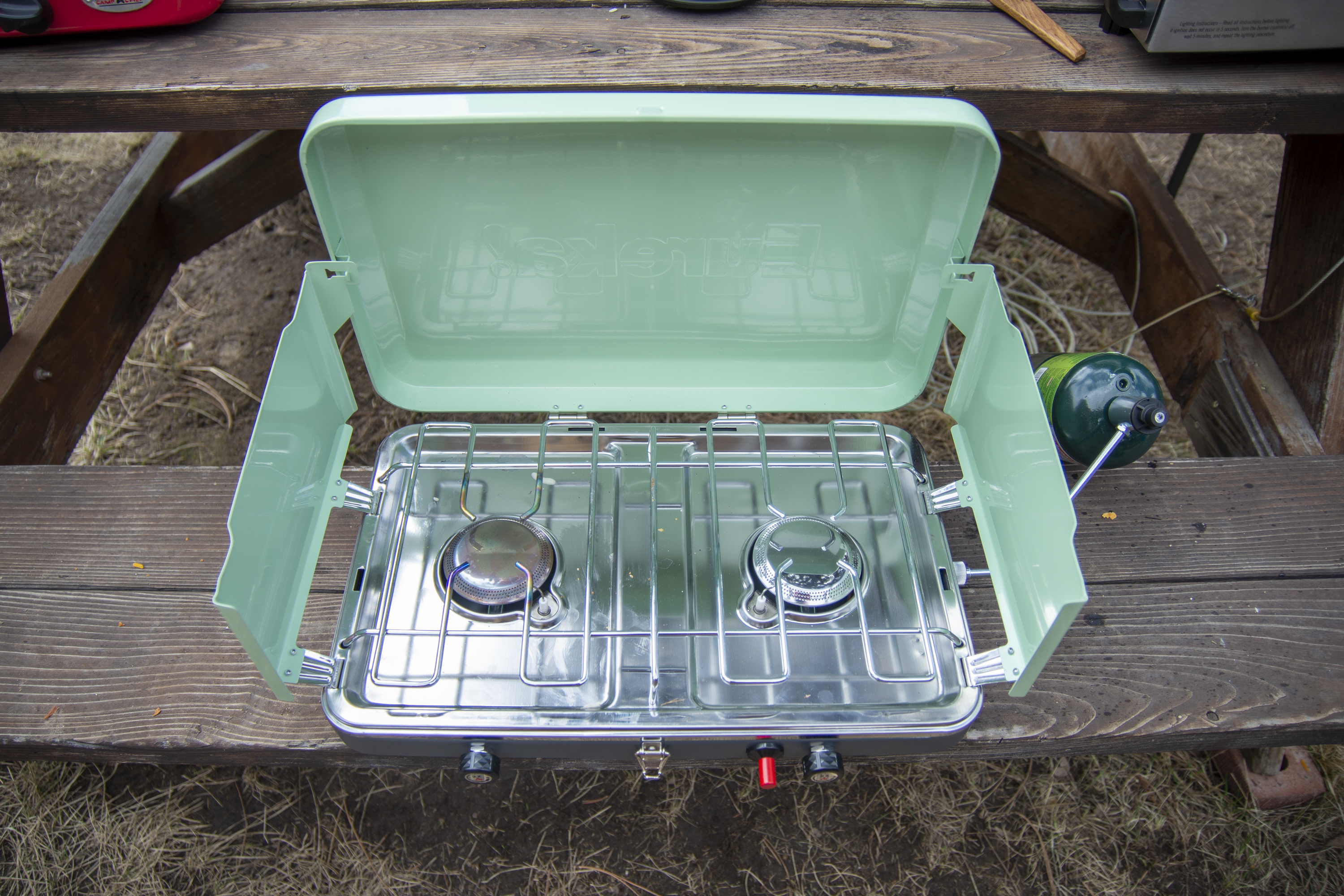 A Eureka Ignite camping stove on a wooden picnic table.