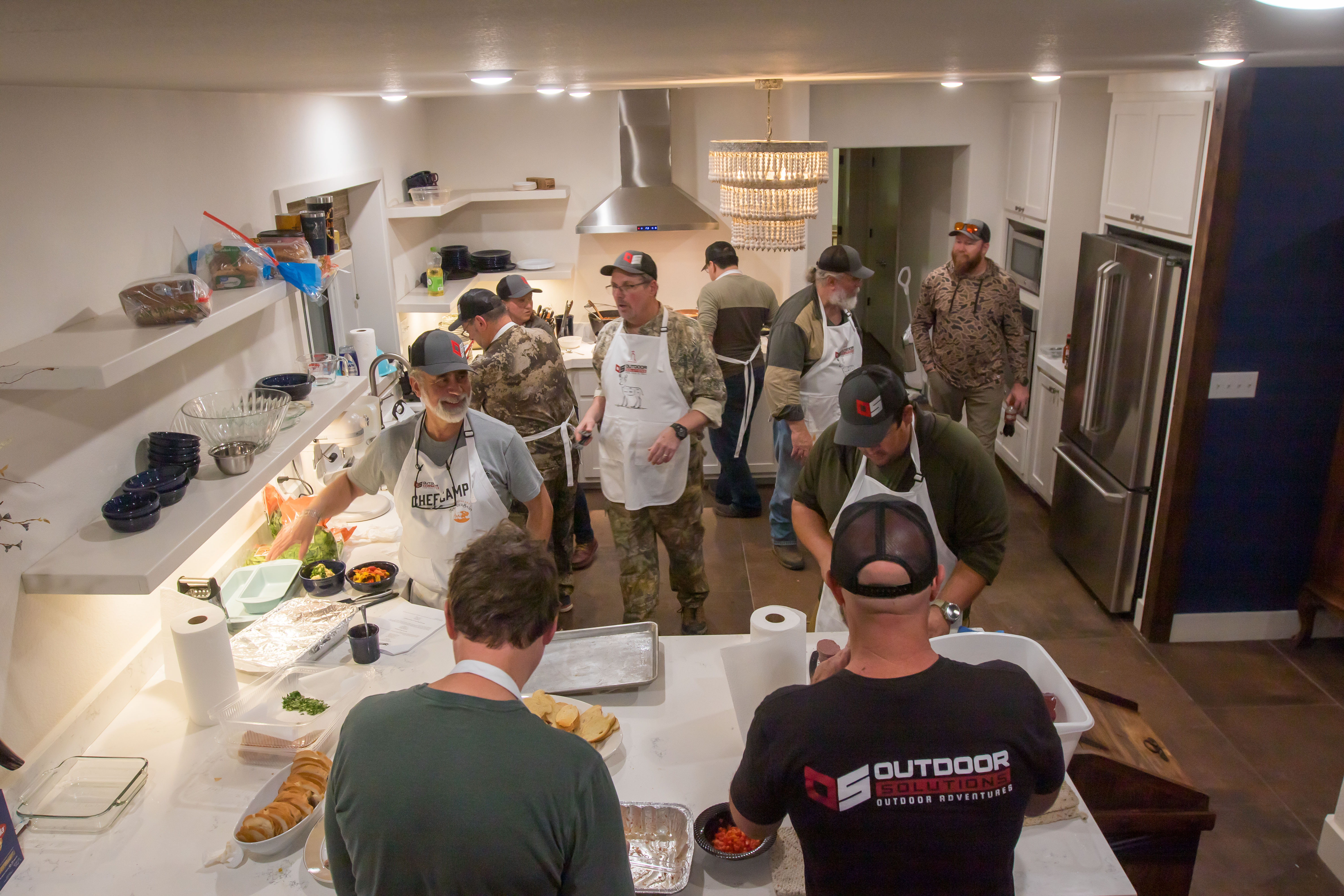 Students and staff working together in a commercial kitchen to prepare a multi-course wild game meal.
