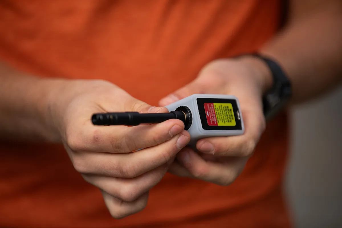 Hands attaching a flexible hose to a small silver Cycplus AS2 Pro electric pump.