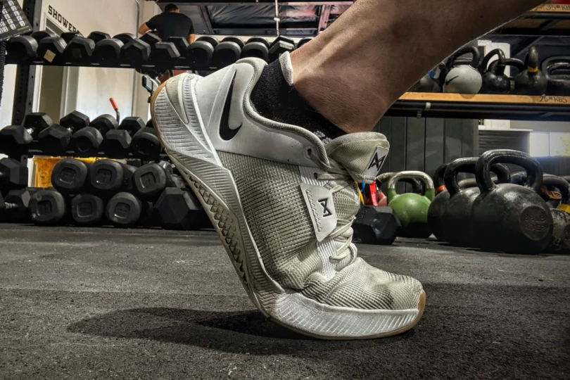 A hand bending the forefoot of the Nike Metcon 10 to demonstrate its flexibility.