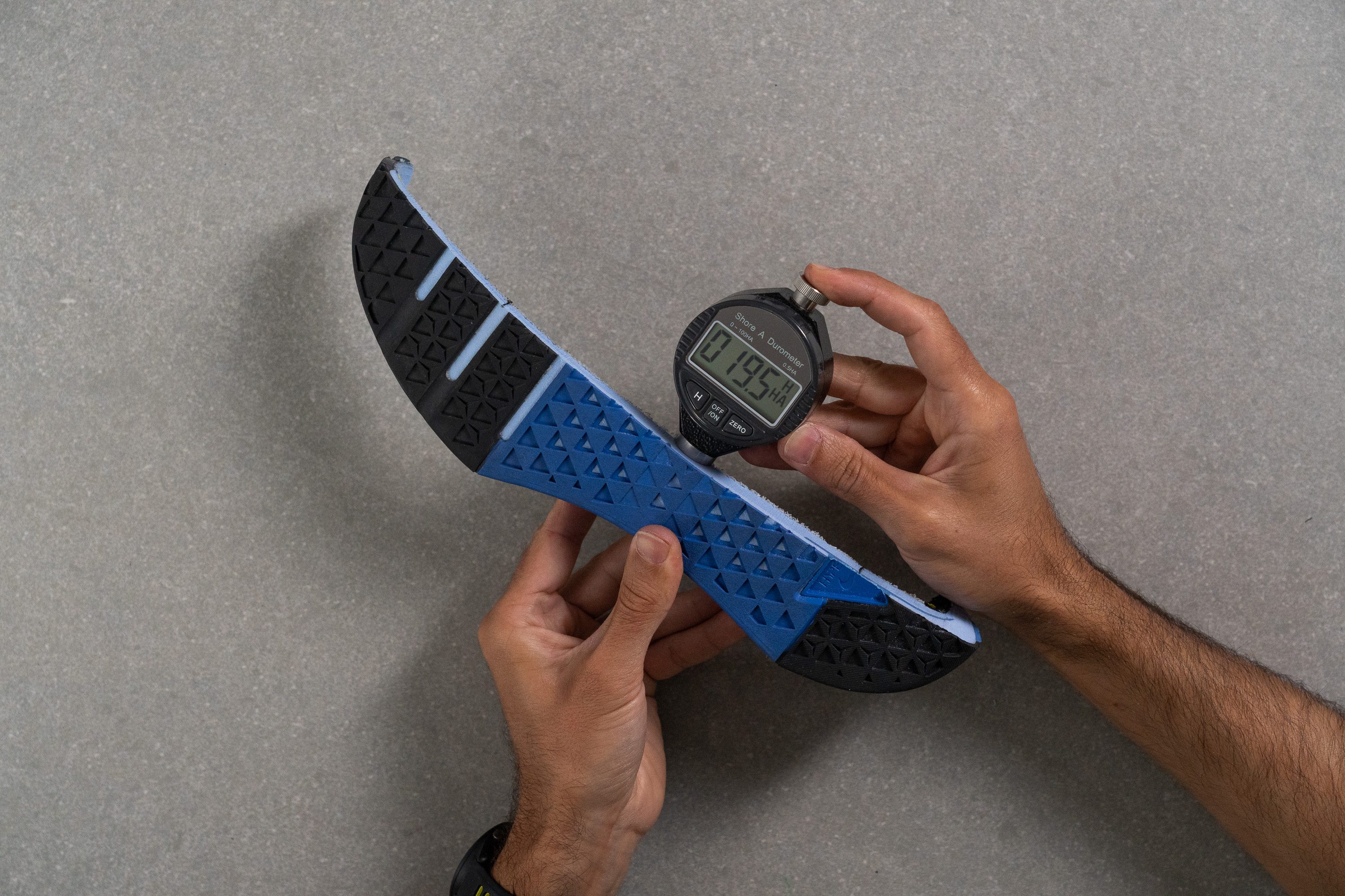 A technician using a durometer tool to test the softness of the Nike Metcon 10 midsole foam.