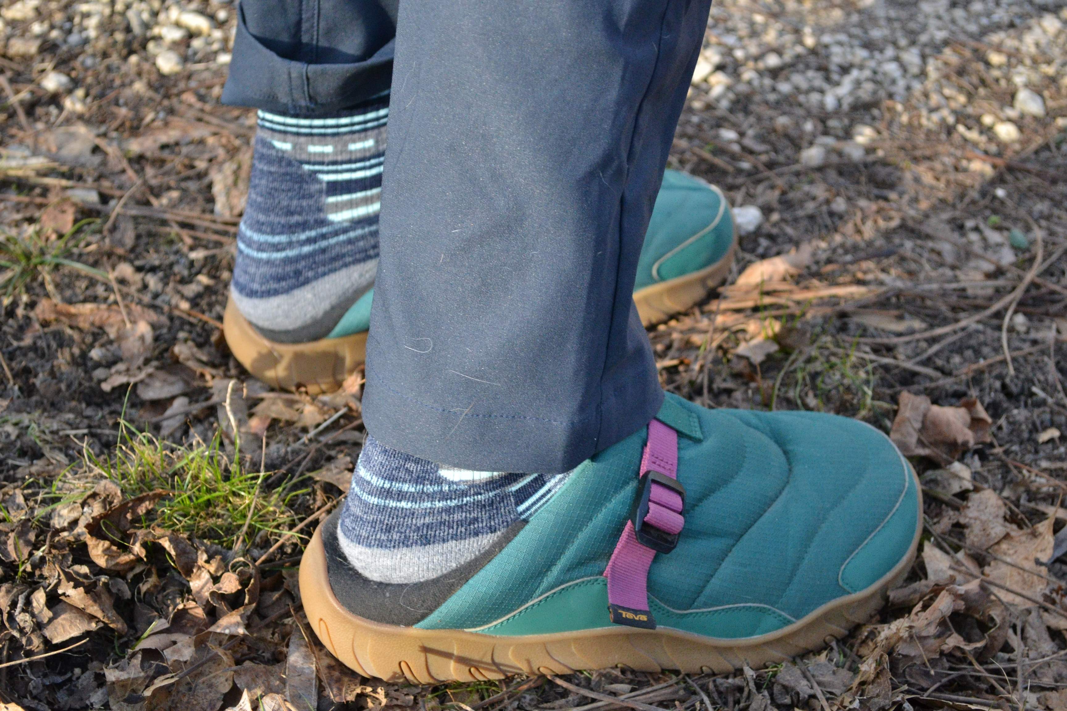 A person wearing the Teva ReEmber slipper in a natural outdoor environment.