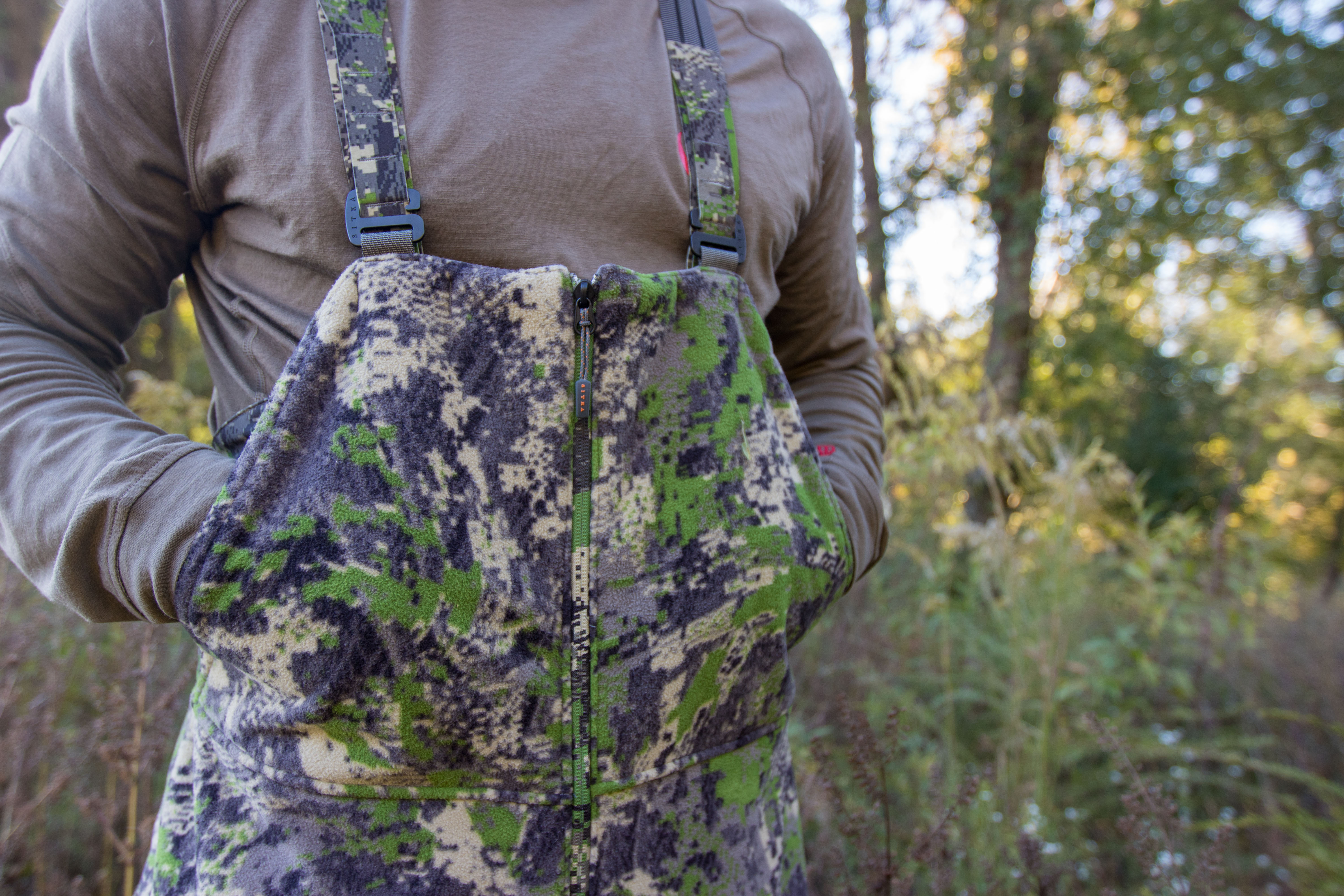A hunter accessing the cargo pockets on a pair of SITKA Stratus 2.0 hunting bibs.