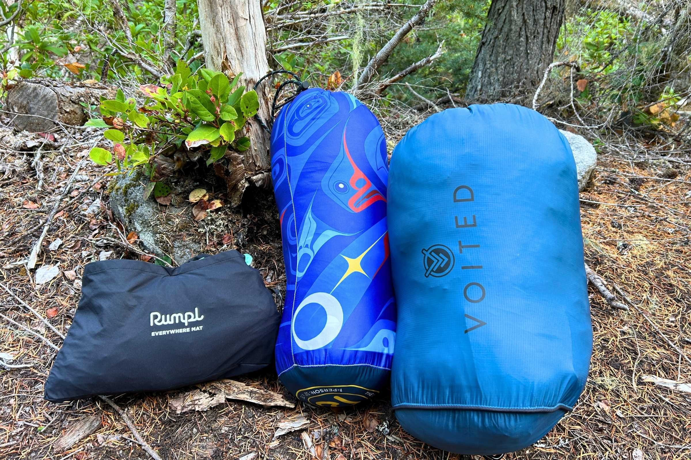 A row of various camping blankets compressed into their respective stuff sacks.