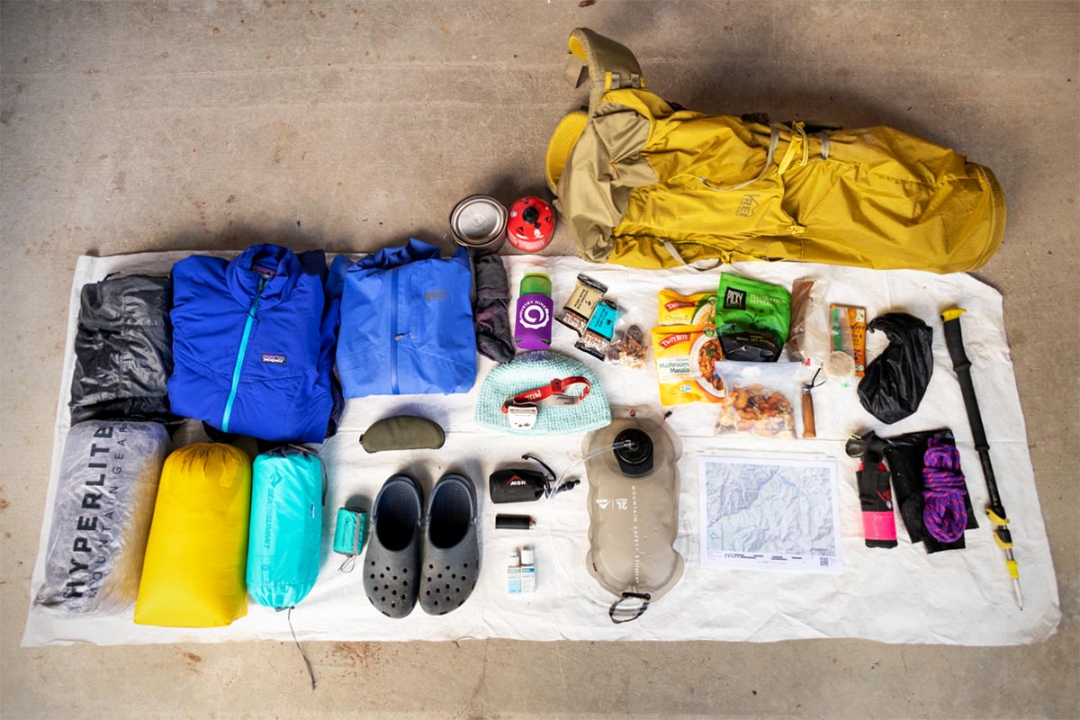 A collection of ultralight backpacking gear including a tent, quilt, and sleeping pad laid out on a groundsheet.