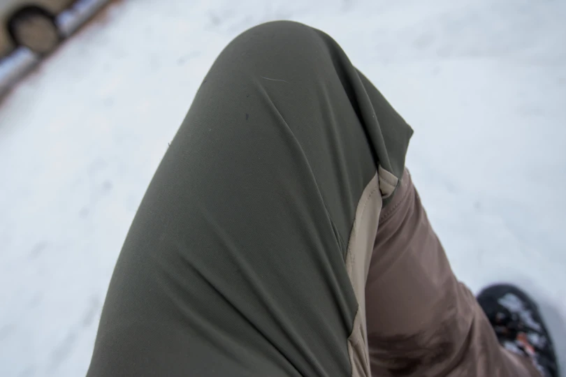 A close-up demonstration of the Kings Camo XKG Field pant fabric being stretched by hand.