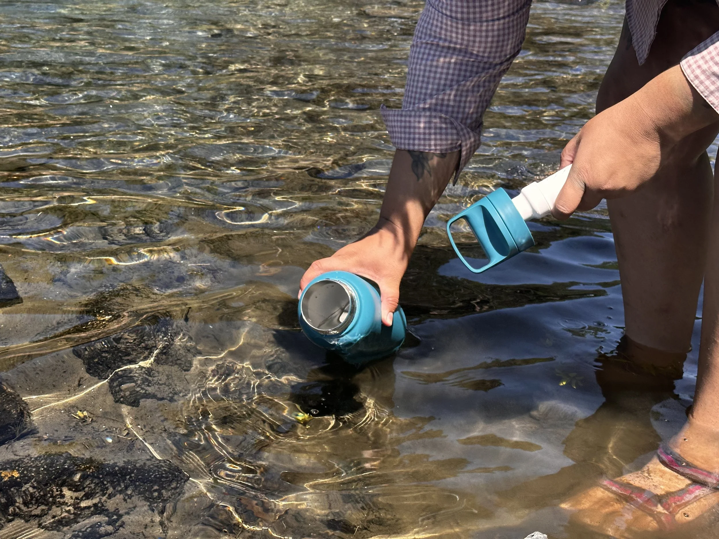 A stainless steel filtered water bottle being used in an outdoor setting.