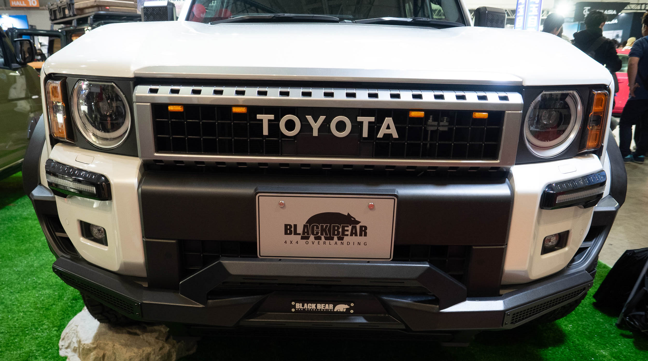 A black Toyota Land Cruiser 250 equipped with a Black Bear rooftop tent on the show floor.