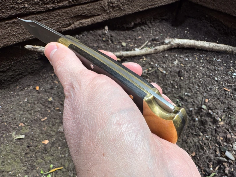 A hand holding a Buck 110 with a focus on the rear locking bar mechanism.