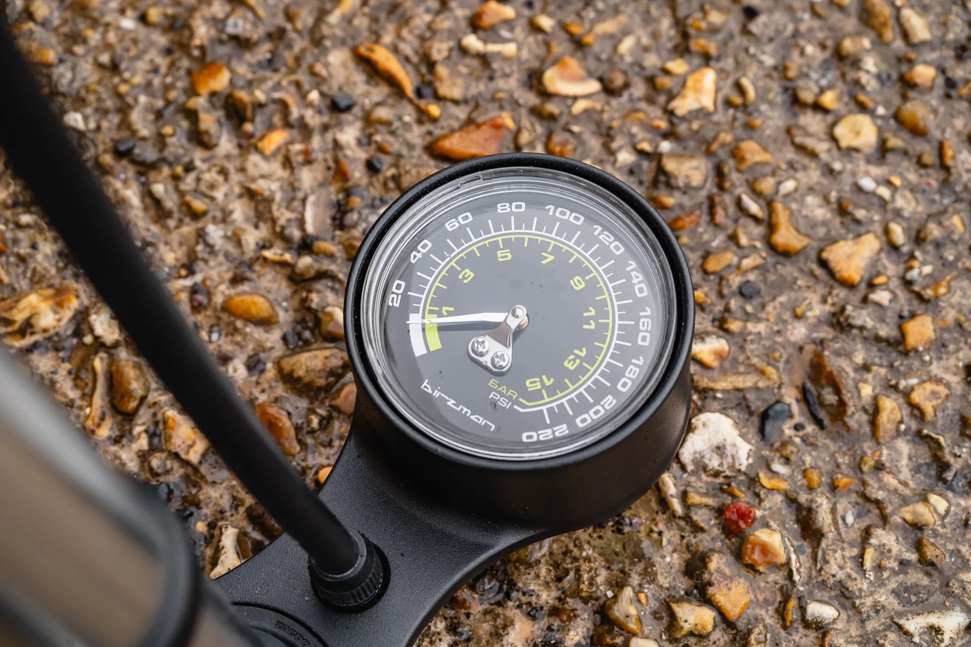 Close-up of a large analog pressure gauge on a floor pump showing PSI and Bar increments.