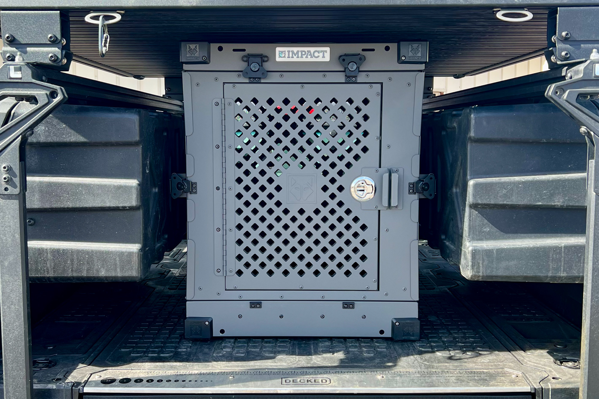 A heavy-duty aluminum dog crate secured in the back of a pickup truck.