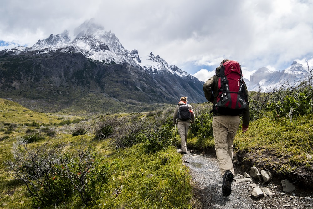 A pair of hiking boots, trekking poles, and a backpack laid out on a wooden floor.