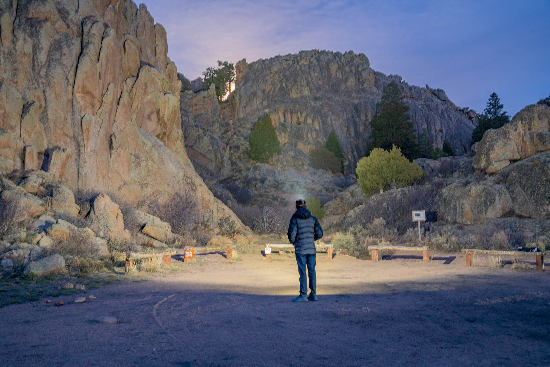 An adventurer wearing a headlamp while scrambling over technical rocky terrain at night.