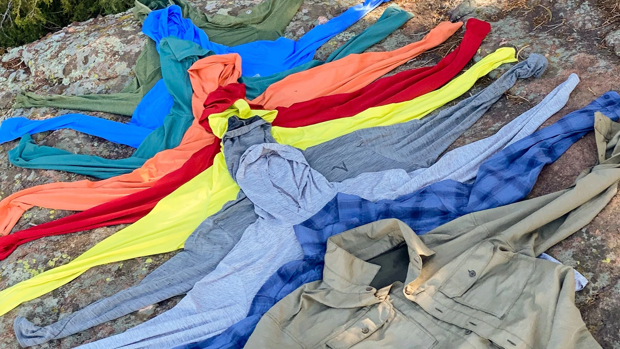 A collection of various men's sun protection shirts and hoodies laid out together.