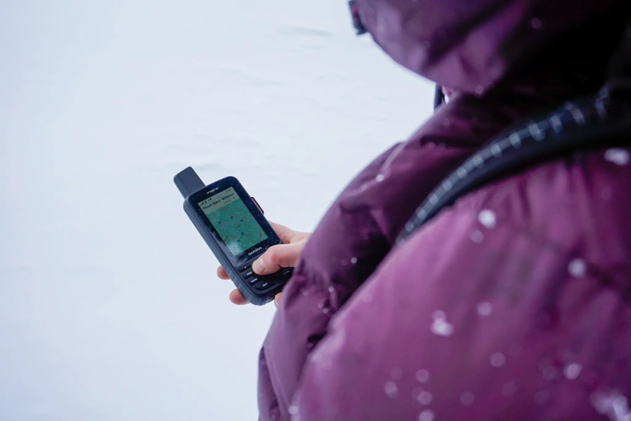 A Garmin GPSMAP series handheld device showing a topographic map while on a winter ski tour.