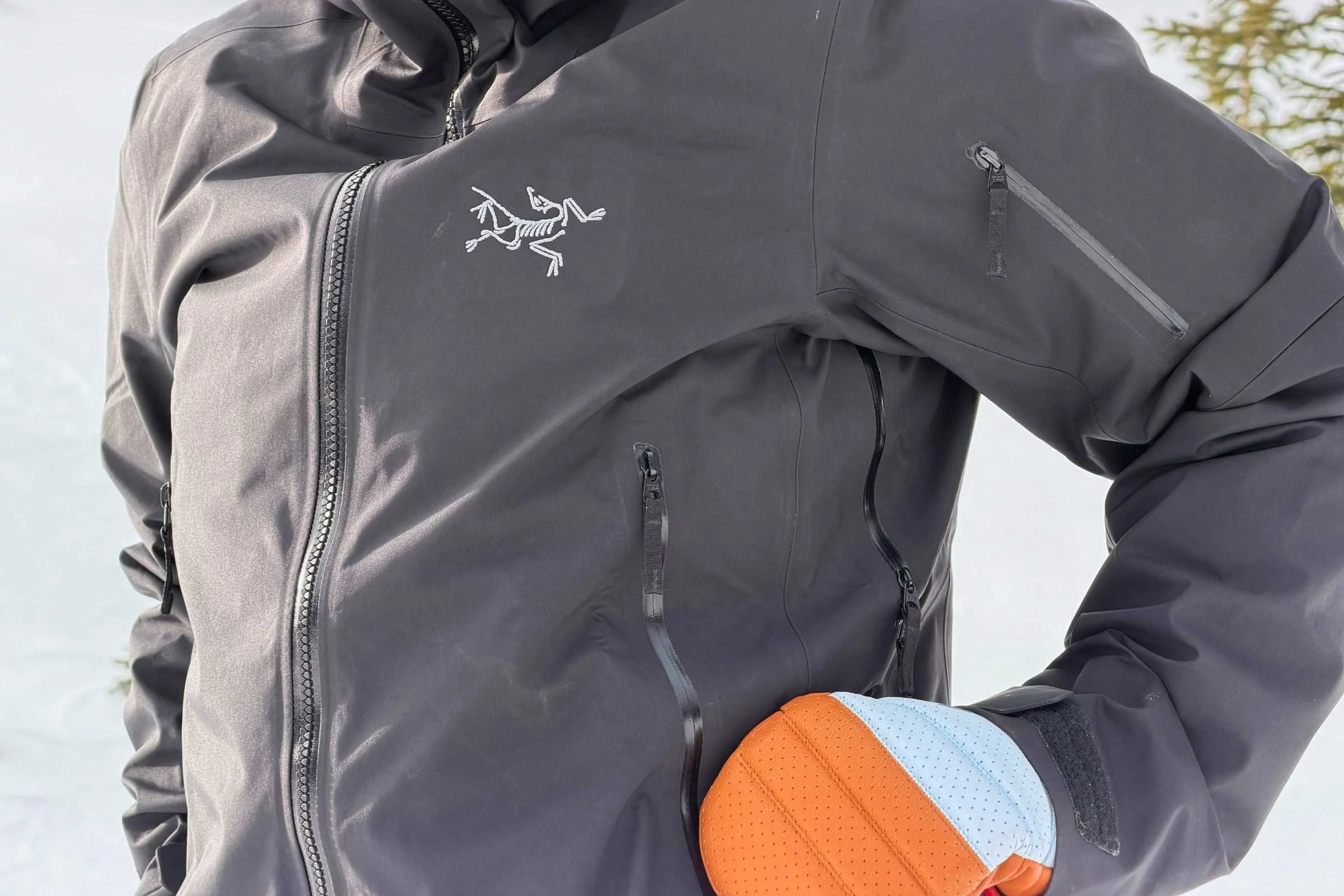 Detailed view of a waterproof zipper and chest pocket on a premium dark red Arc'teryx jacket.