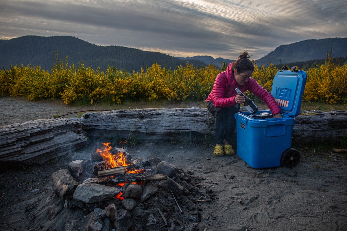 A hand pulling a tall bottle of wine out of a Yeti Roadie 48 cooler, showing its vertical depth.