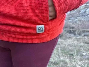 A close-up shot of the kangaroo-style front pockets on a blue fleece pullover.