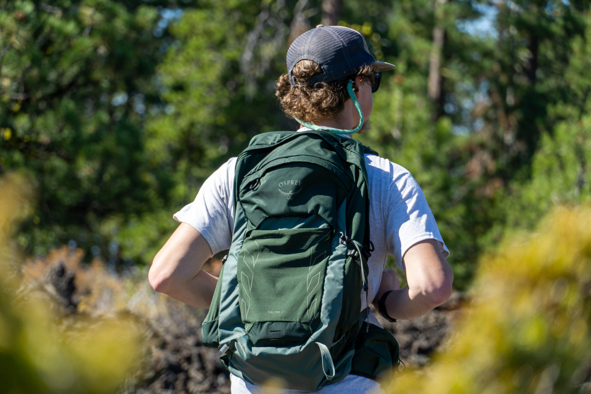 A person using an Osprey travel backpack in a scenic outdoor setting.