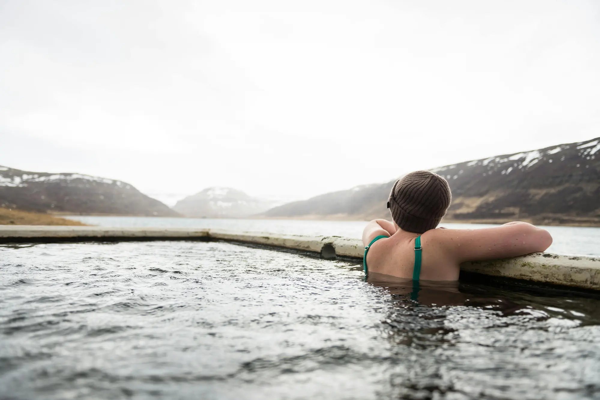A woman practicing cold water therapy in an outdoor tub surrounded by snow.