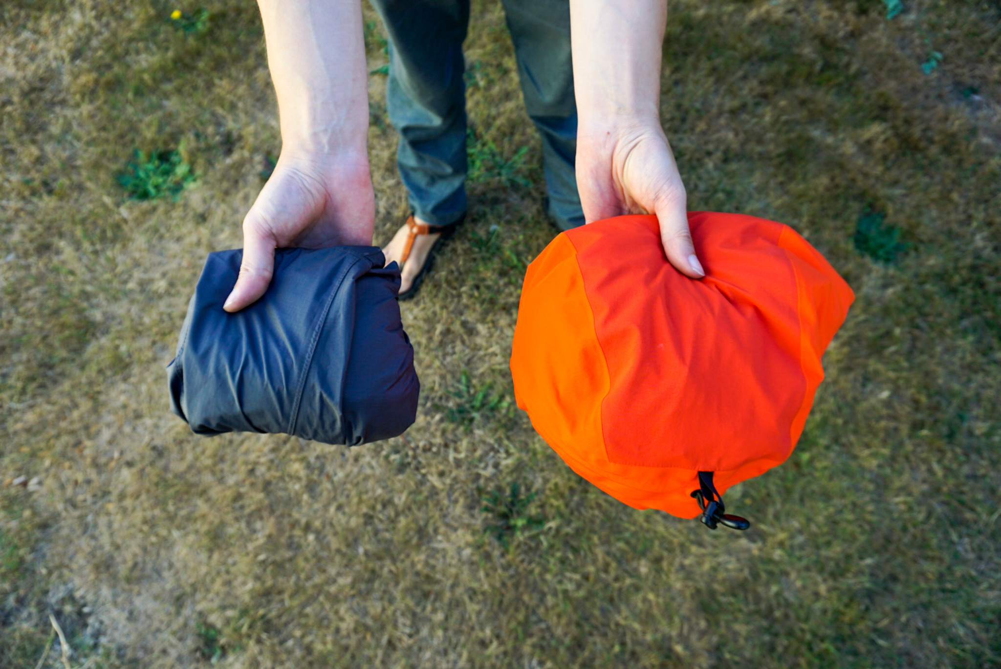 Three different rain jackets packed into their own pockets to compare their compressed sizes.