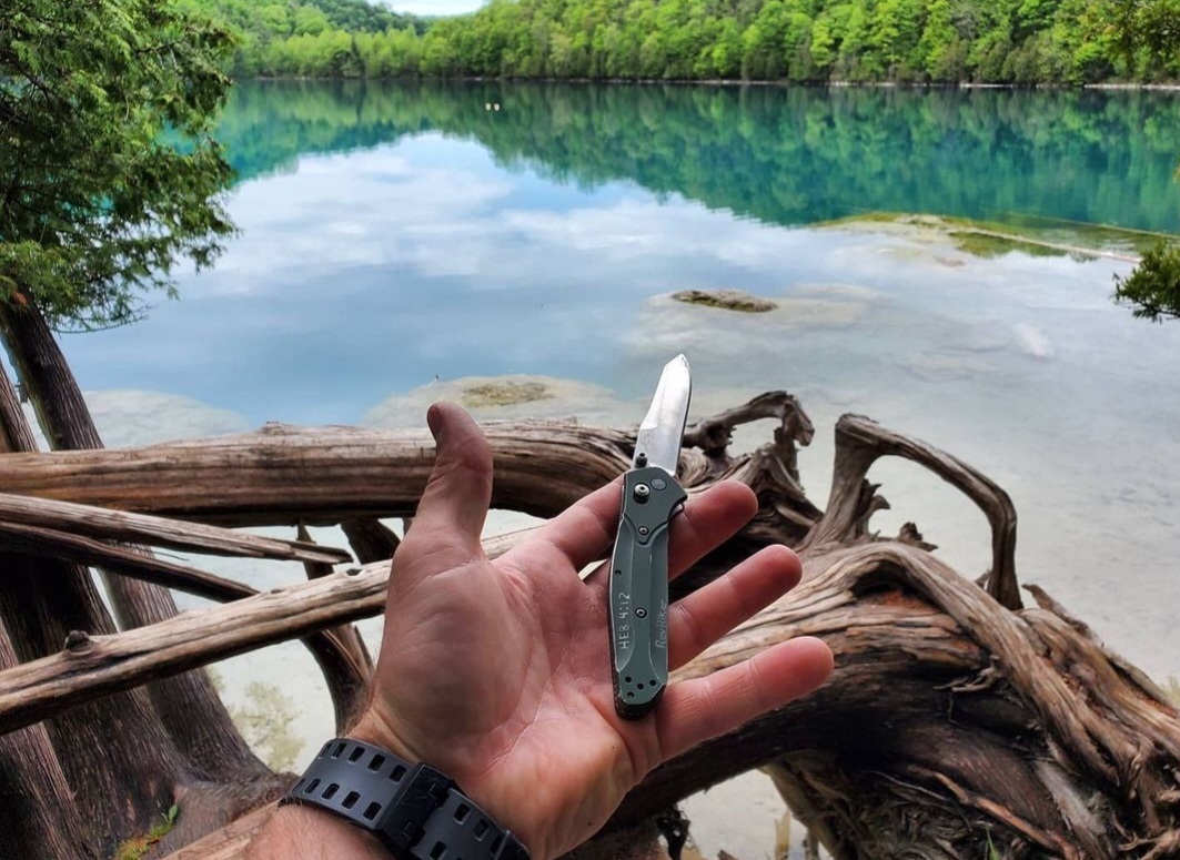 A person holding the classic Benchmade 940 pocket knife in an outdoor setting.