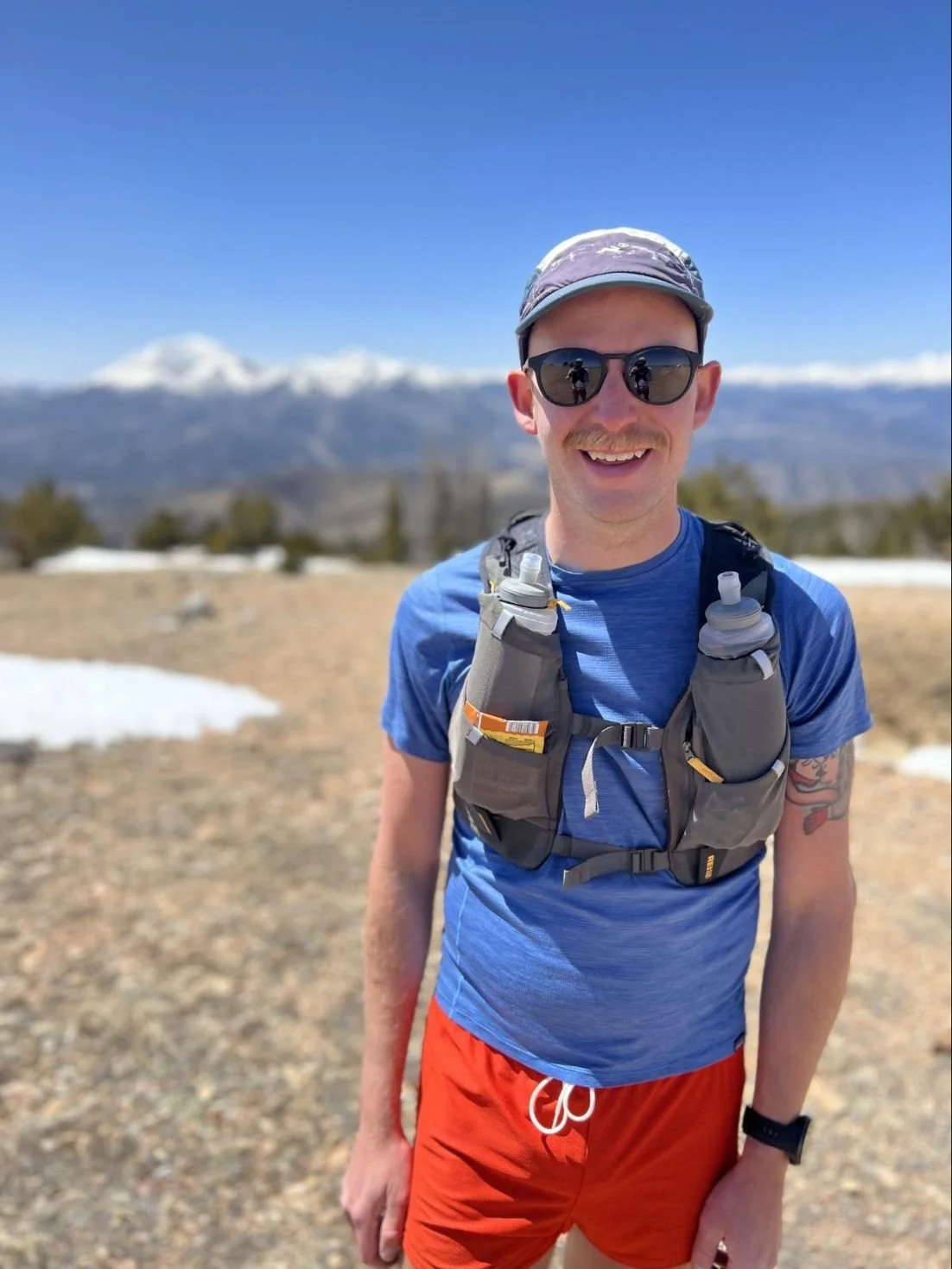 A runner wearing a technical shirt standing in the Sangre de Cristo mountains.