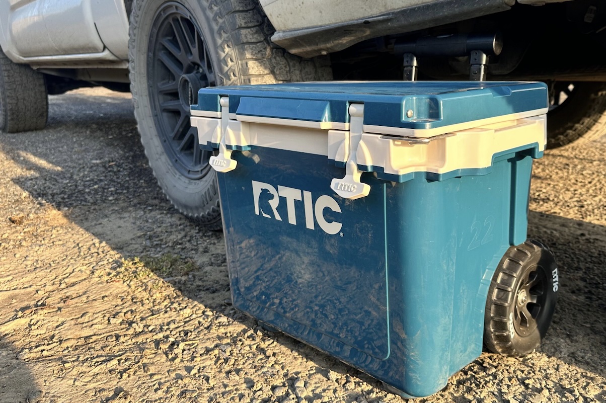 A compact 22-quart RTIC Ultra-Light cooler being prepared for a trip near a vehicle.