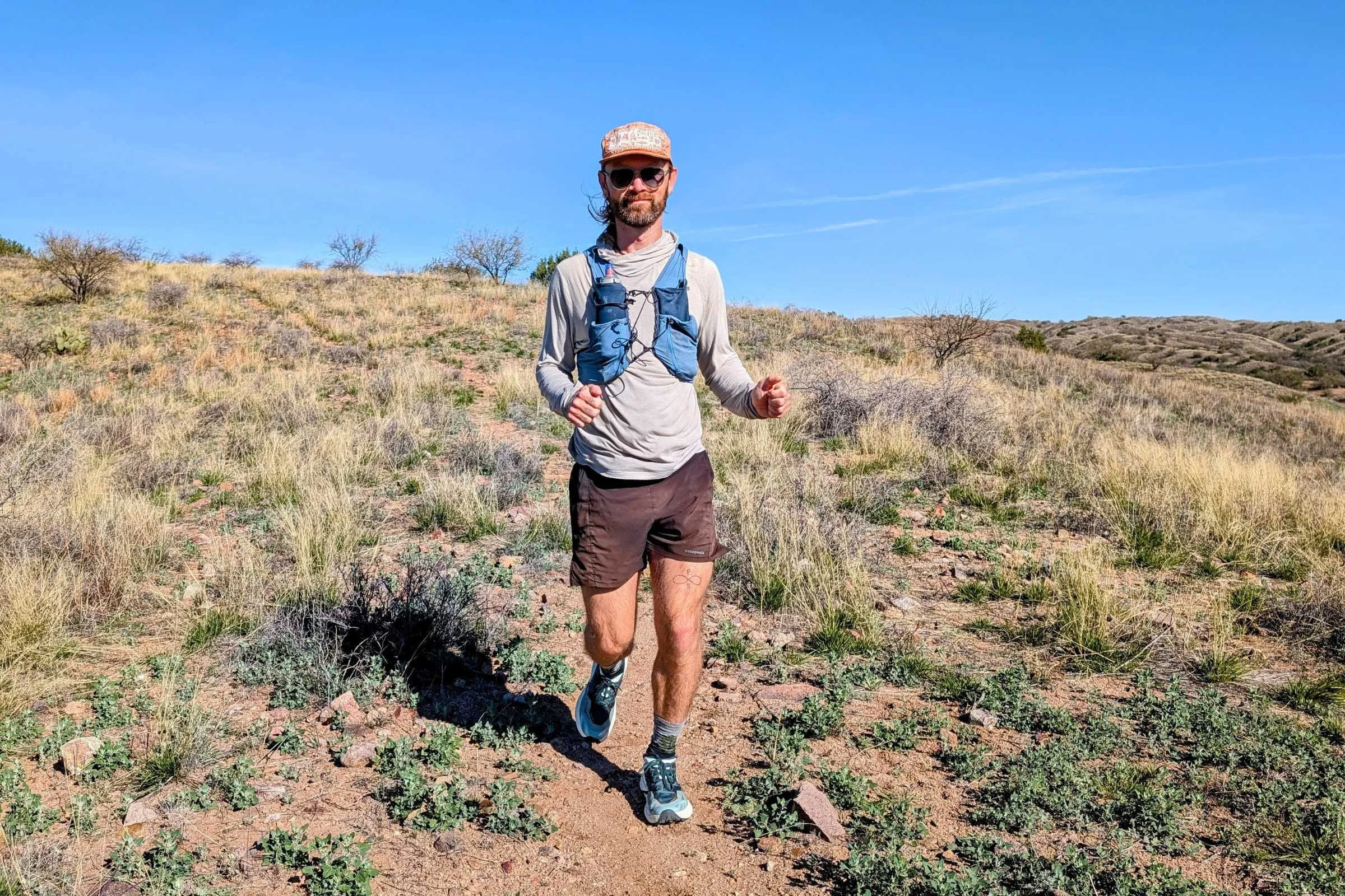 A pair of HOKA Speedgoat 7 shoes on a dusty, rocky trail in a desert environment.