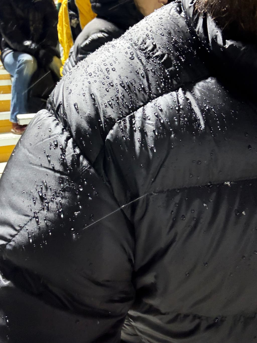Close-up of water droplets beading on the technical fabric of a down jacket.