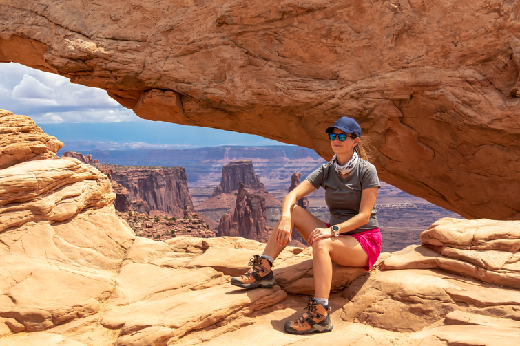 A hiker sitting on a rock in a shaded area of the canyon floor, resting during a trek.