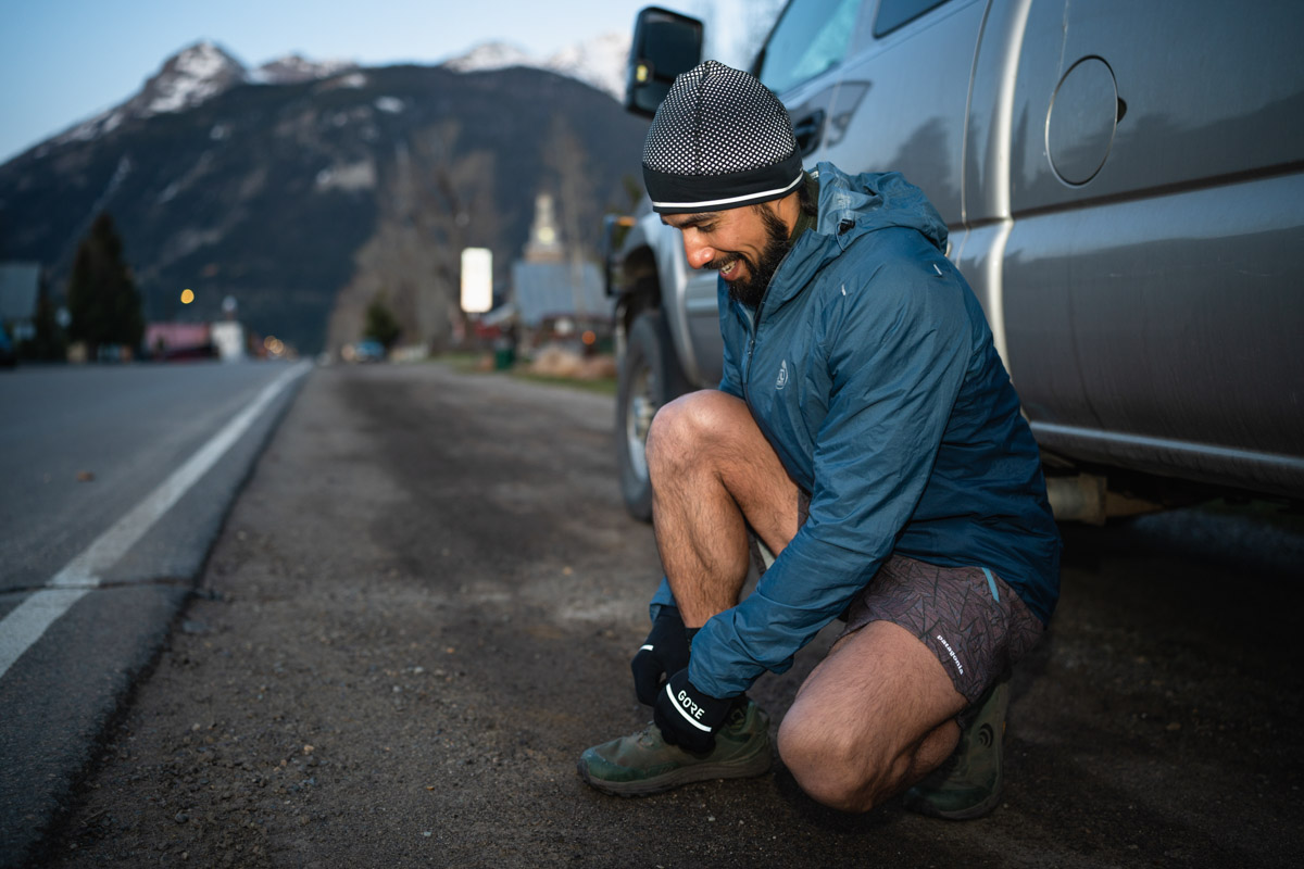 Hands in winter gloves successfully tying the laces of a running shoe.
