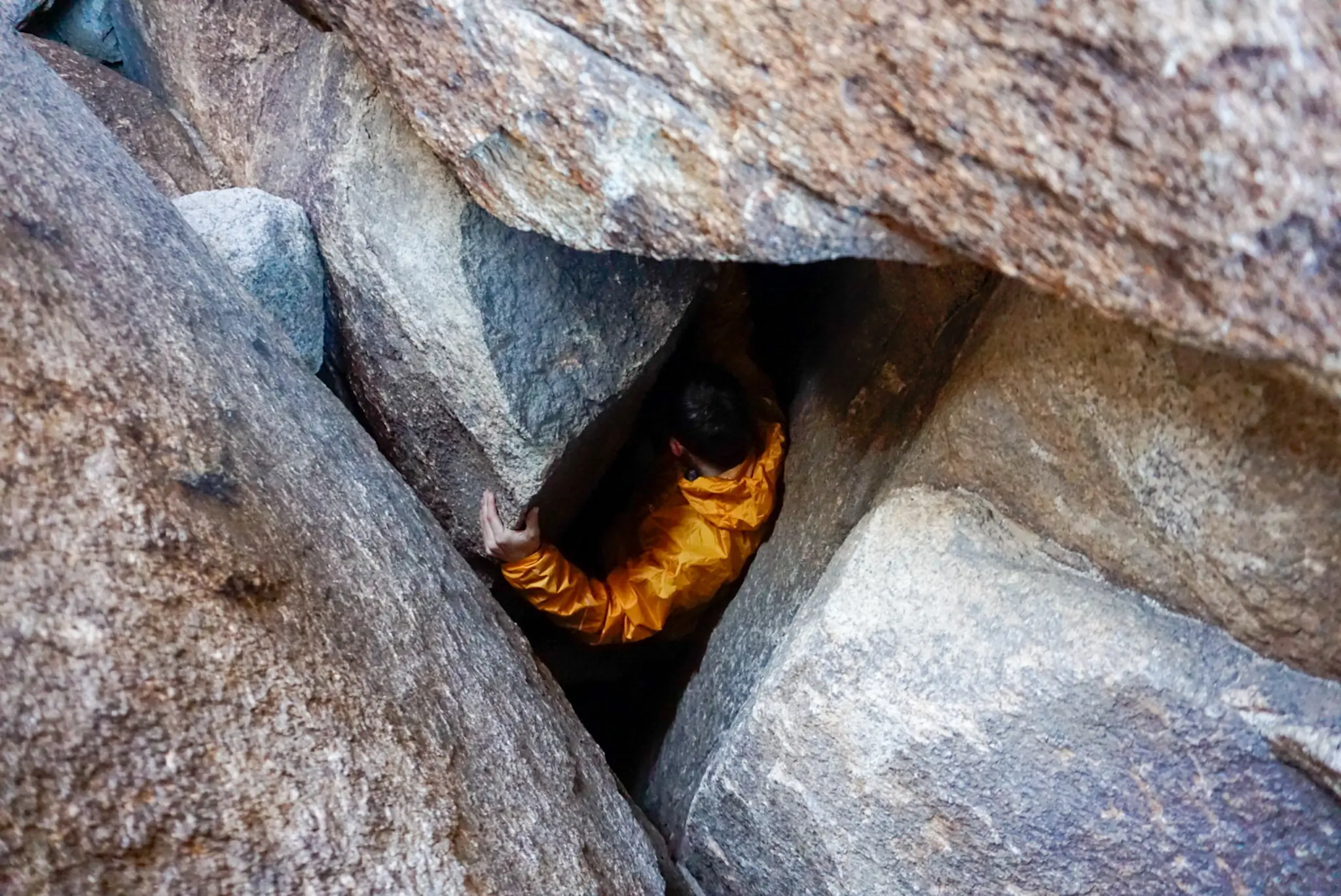 A climber wearing an Outdoor Research Helium jacket while scaling a rock face.