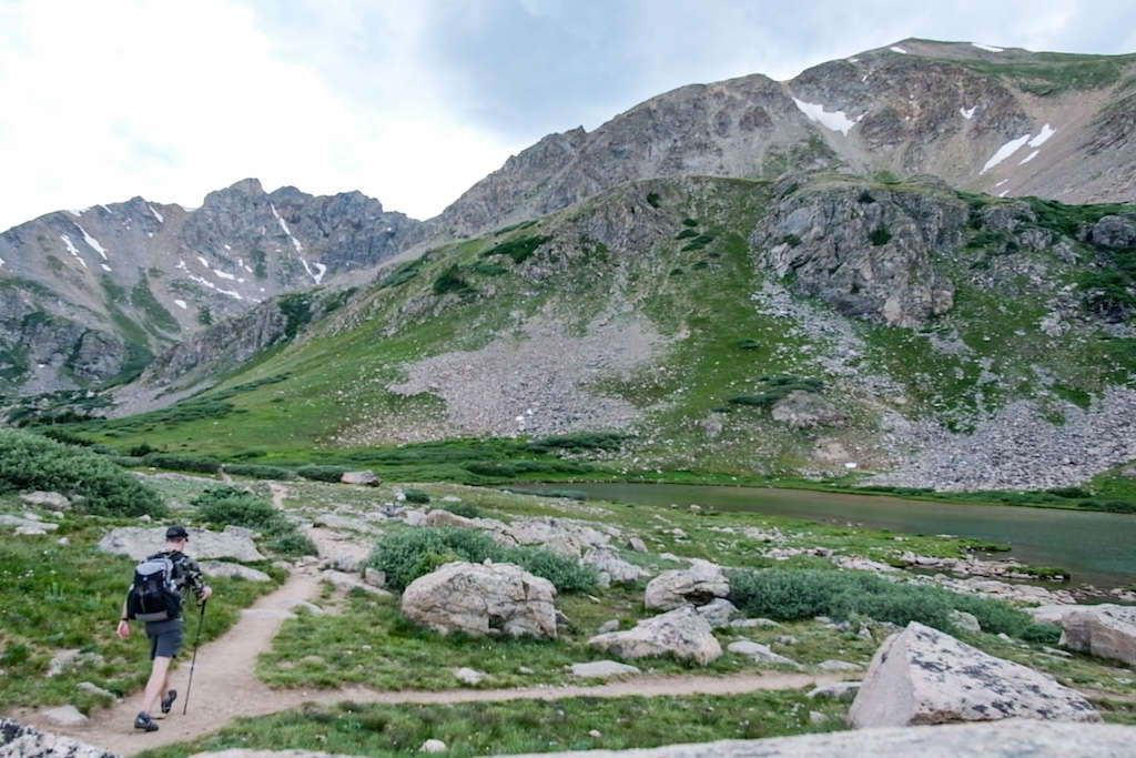 Hiker descending a high alpine mountain trail.