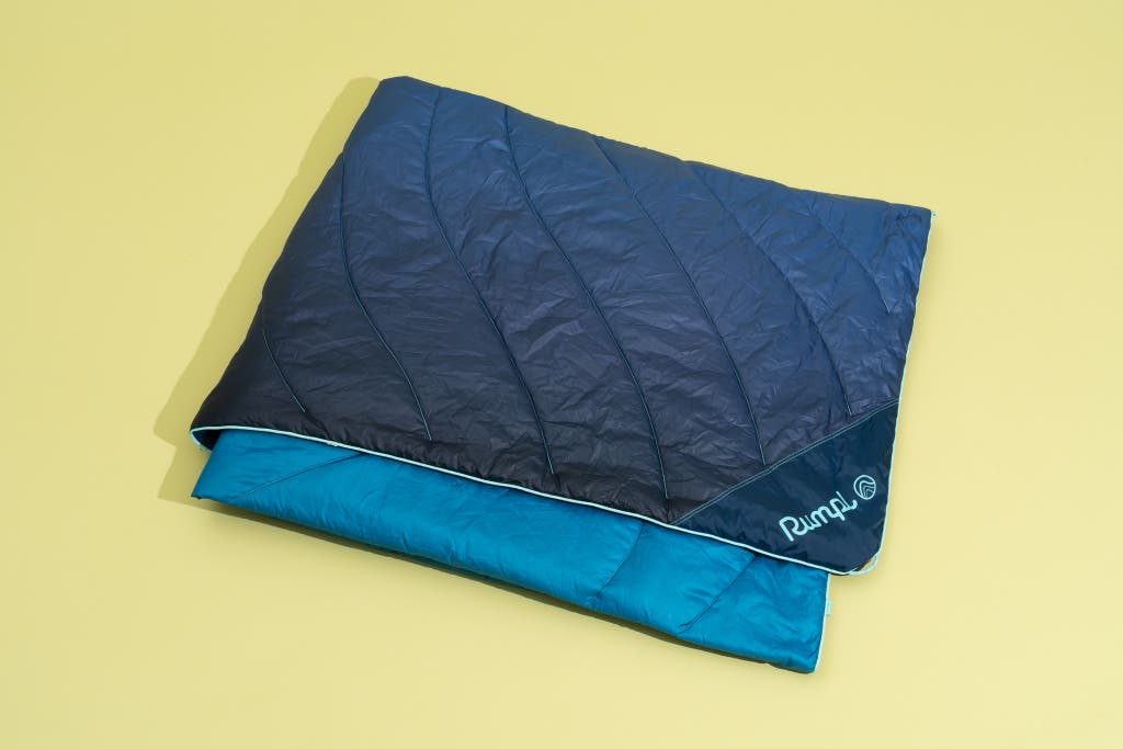 A folded Rumpl Original Puffy Blanket in the Ocean Fade blue color scheme.