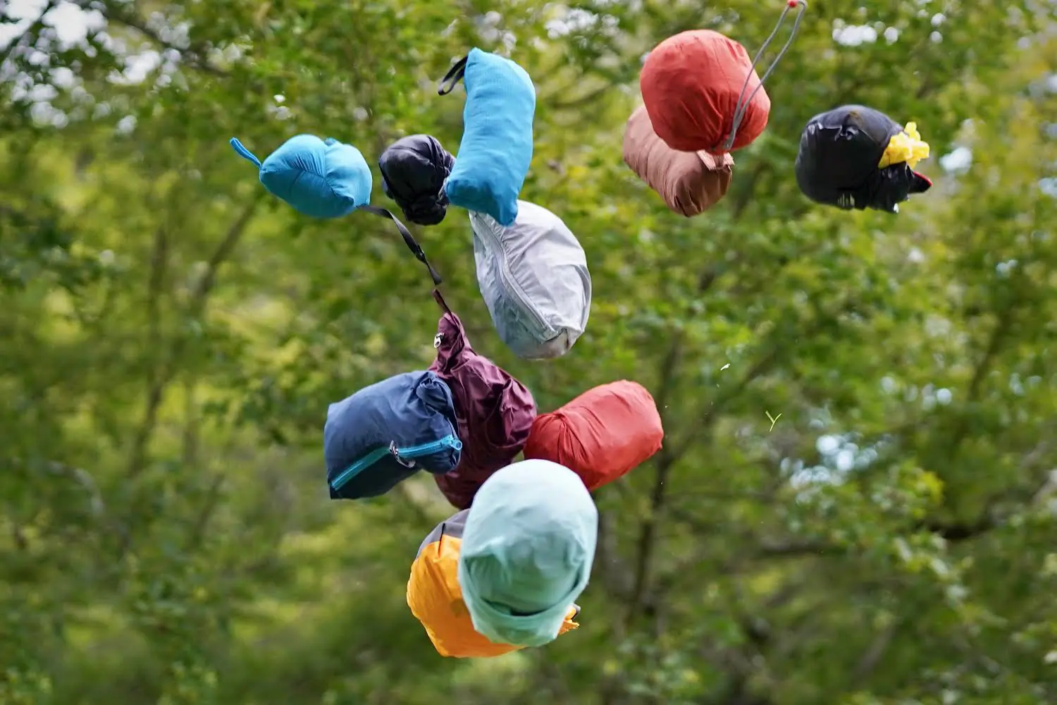 Several windbreakers compressed into small stuff sacks being tossed into the air.