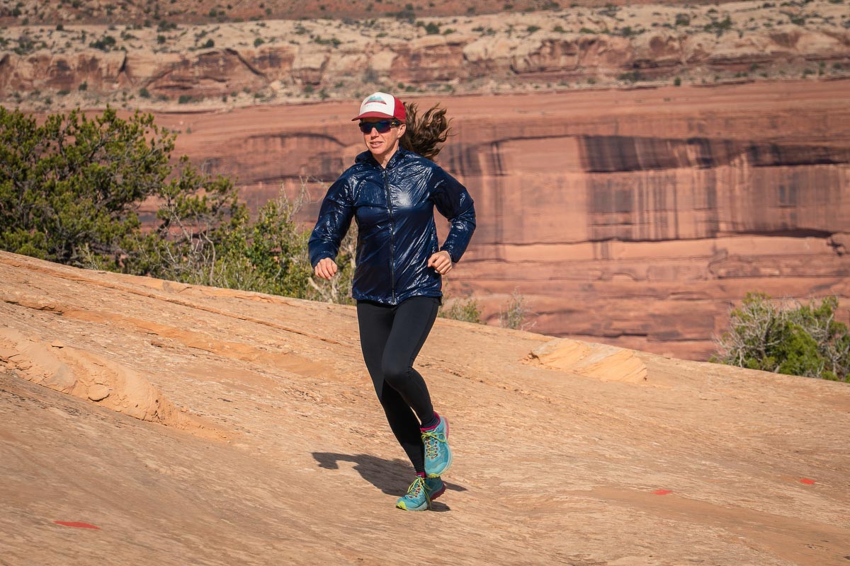 A hiker wearing the translucent Enlightened Equipment Copperfield Wind Shirt on a trail.