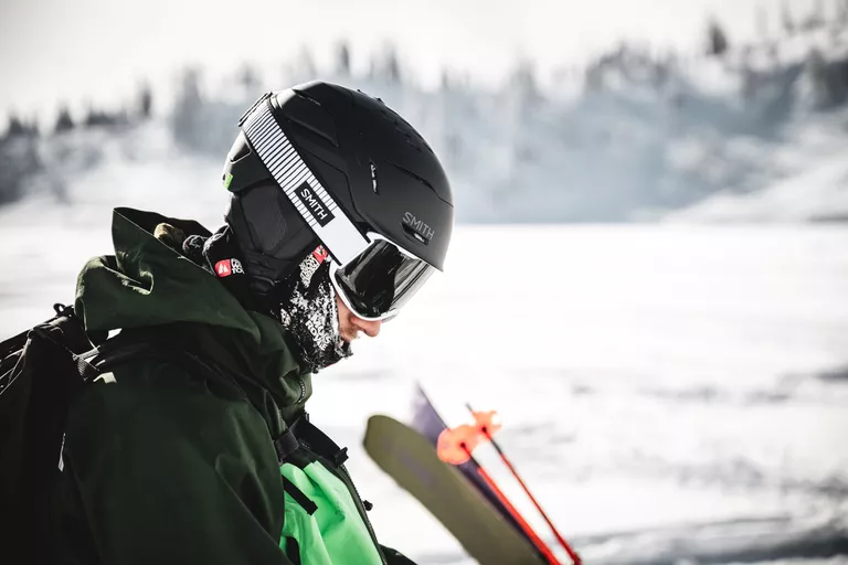 Close-up of a skier wearing a professional helmet and goggles in mountain conditions.