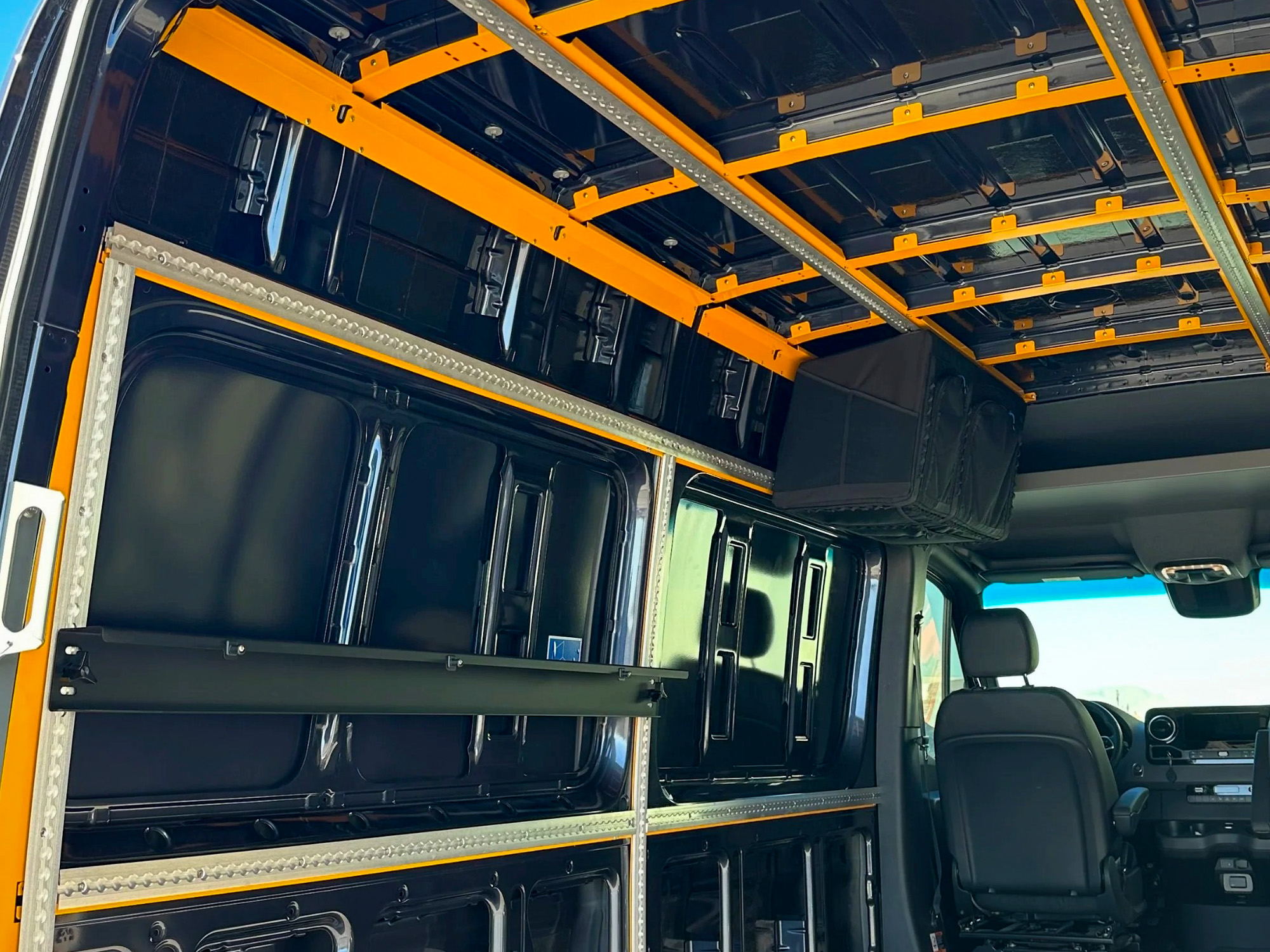 Interior view of a van chassis with a black powder-coated steel foundation kit installed.