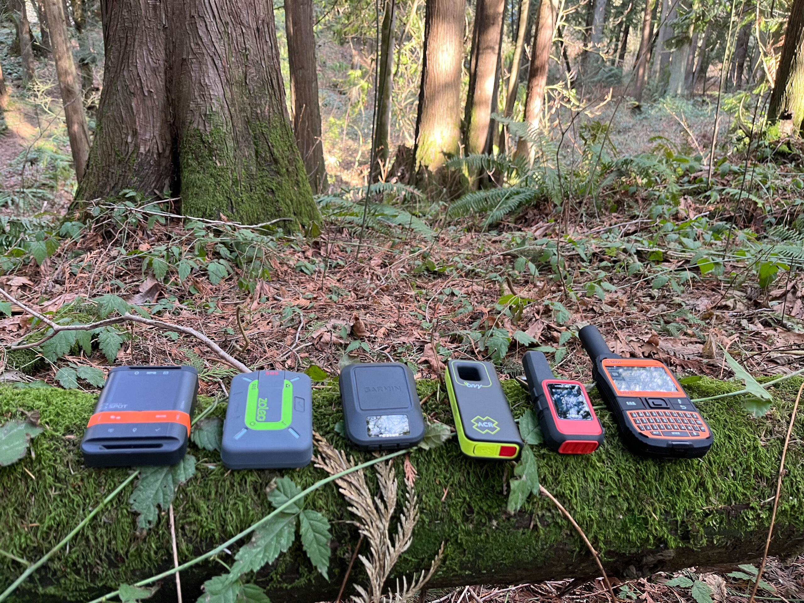 A lineup of various satellite messaging devices including Garmin and competitor models.