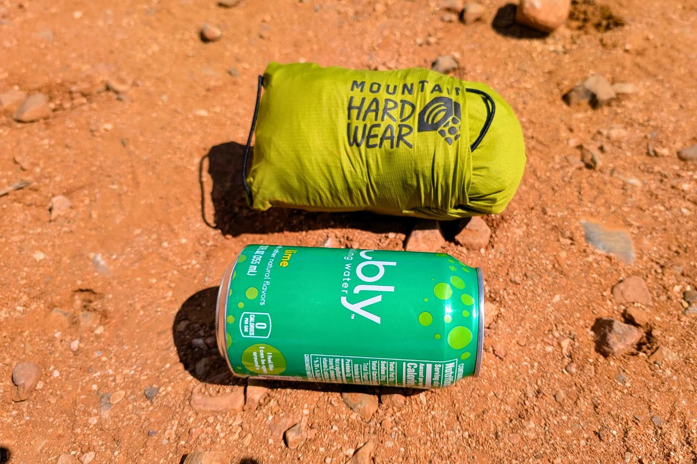Mountain Hardwear Kor Airshell jacket packed into its own pocket next to a soda can.