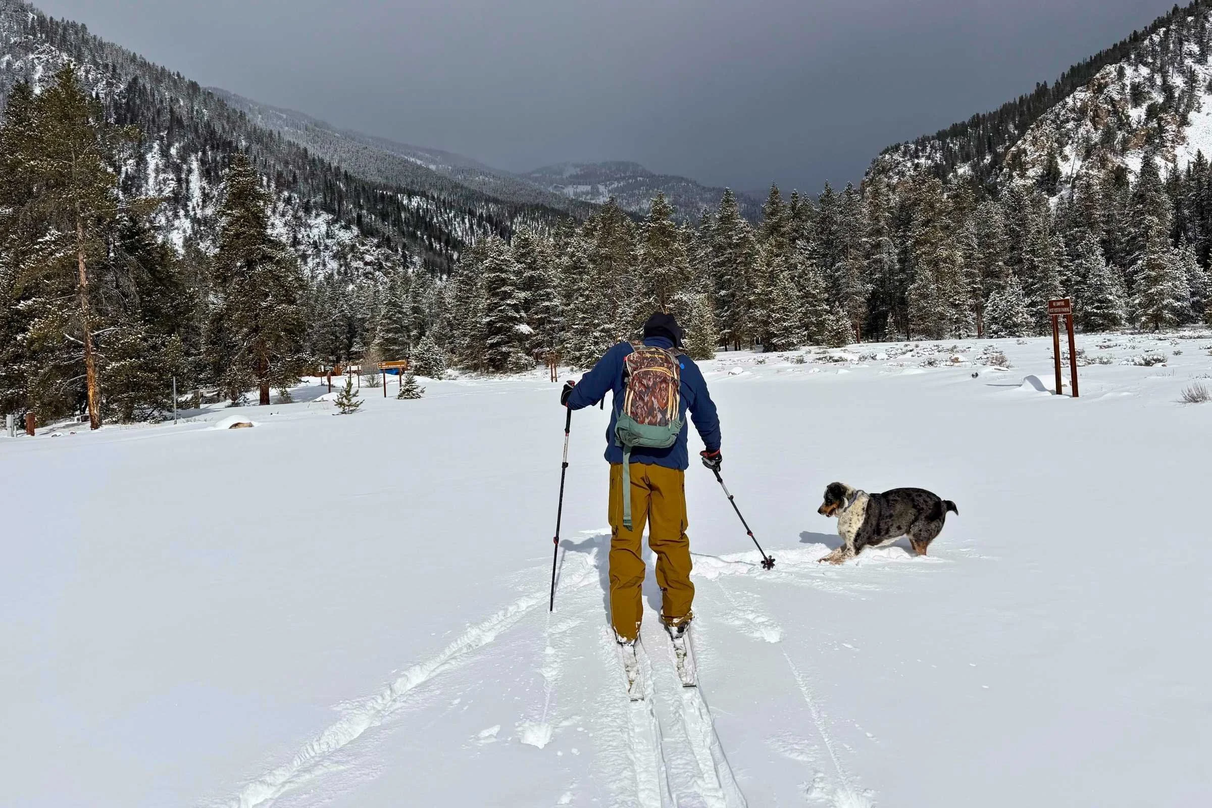 A Garmin inReach Mini 3 Plus mounted on the shoulder strap of a ski pack in snowy conditions.